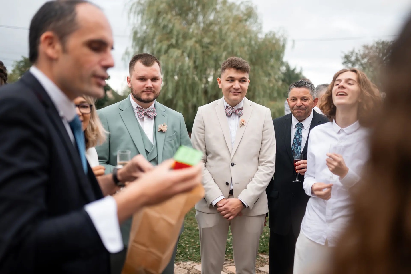 Invités d'un mariage captivés par un tour de magie close-up de Benoît